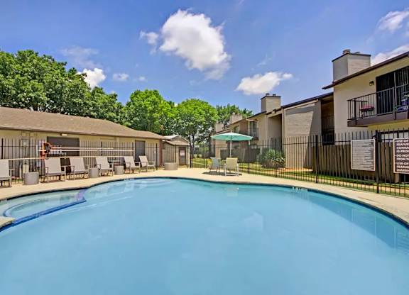 Swimming pool with lounge chairs and surrounding buildings at South Meadows Apartments, Red Oak, Texas