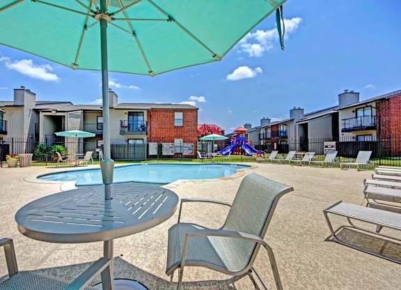 Pool deck with umbrella table and lounge chairs at South Meadows Apartments, Red Oak, 75154
