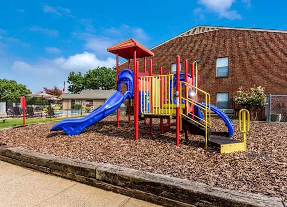 Playground equipment with blue slides and climbing structure at South Meadows Apartments, Red Oak