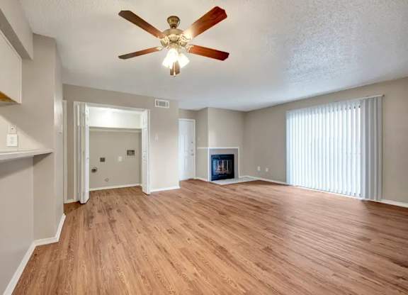 Open concept living area with ceiling fan and fireplace at South Meadows Apartments, Texas