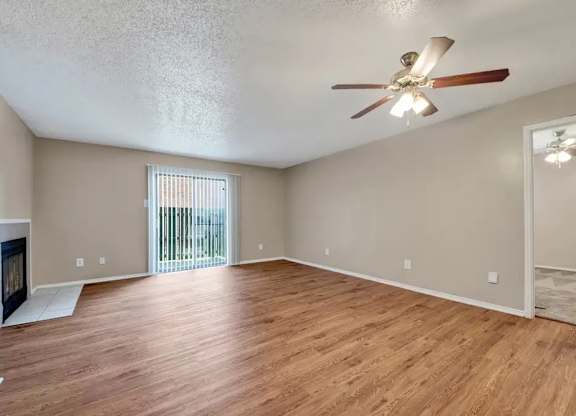 Spacious living room with hardwood style flooring and ceiling fan at South Meadows Apartments, Red Oak, TX 75154