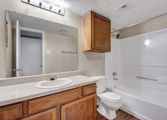 Bathroom with tub shower combo and wood vanity at South Meadows Apartments, Texas