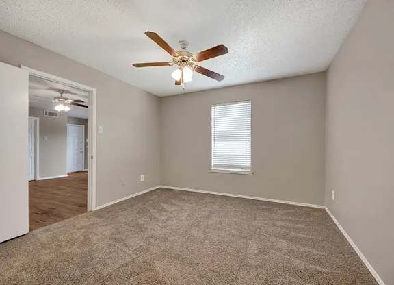 Carpeted bedroom with window and ceiling fan at South Meadows Apartments, Texas