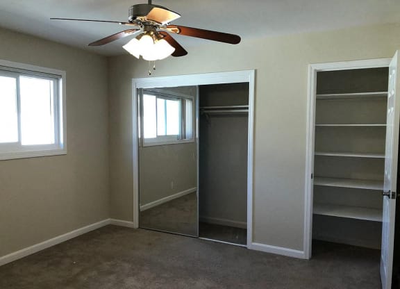 a bedroom with a closet and a ceiling fan