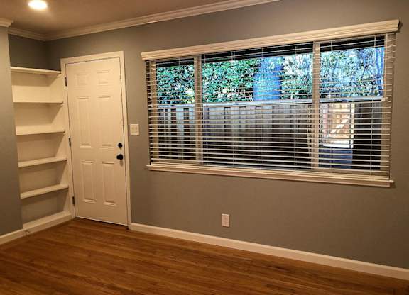 A room with a white door and a window with blinds.