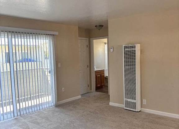 A room with a carpeted floor and a sliding glass door.
