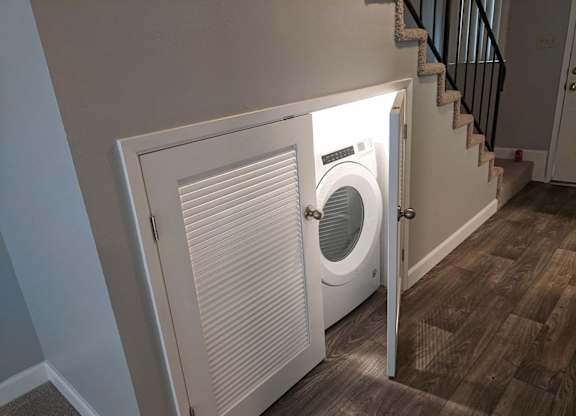 A white washing machine is in a white door.
