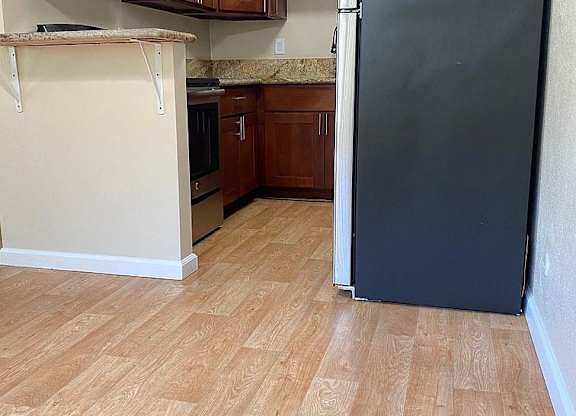 a kitchen with a black refrigerator and wooden floors