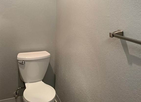 A white toilet in a bathroom with a silver grab bar.