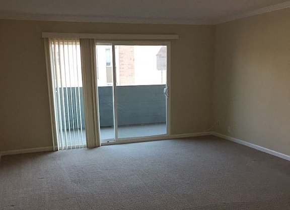 A room with a carpeted floor and a sliding glass door.