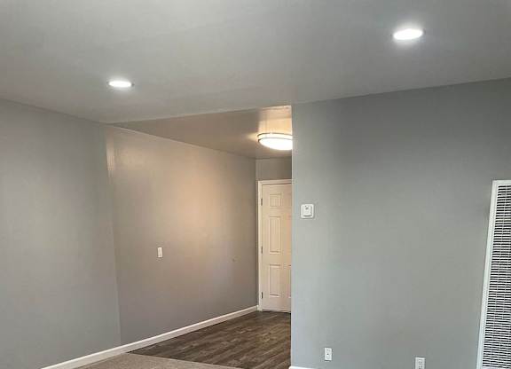 A room with a carpeted floor and a door in the background.