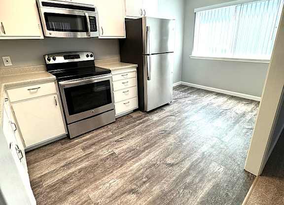 A kitchen with white appliances and a fan.