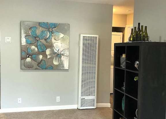 A room with a painting of blue flowers on the wall and a black bookshelf.