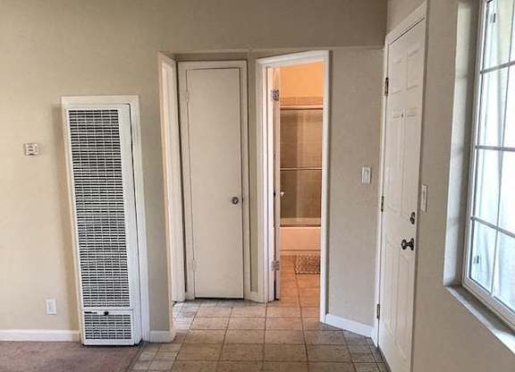 A room with a carpeted floor, a door, and a window.