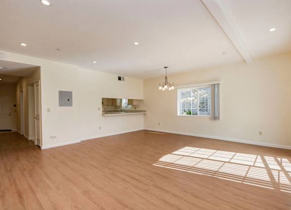 A spacious room with wooden floors and a large window.