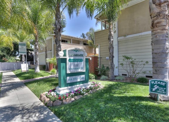 a sign in front of an apartment buildingwith palm trees