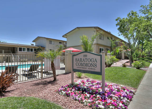 A sign for SARATOGA COMMONS in front of a pool.