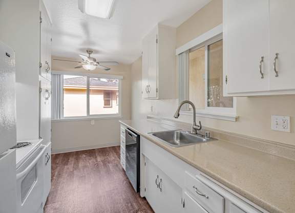 A kitchen with white cabinets and a marble countertop.