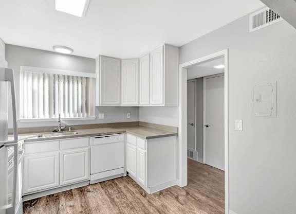 A kitchen with white cabinets and a refrigerator.
