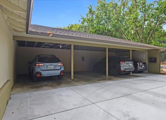 A carport with three cars parked inside.