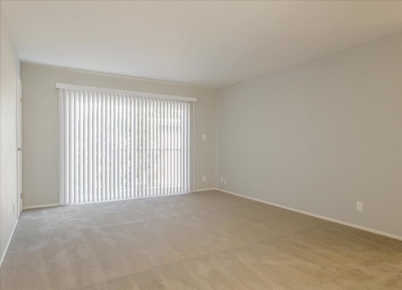 an empty living room with a window and blinds