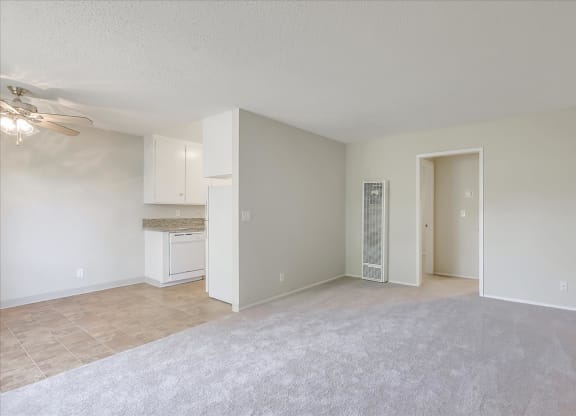 an empty living room and kitchen with a ceiling fan