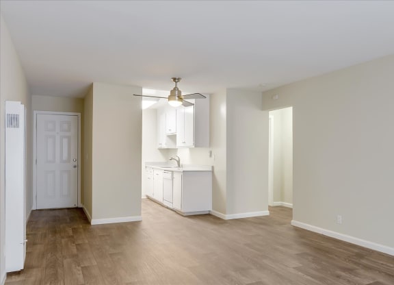 an empty living room and kitchen with white walls and wood floors