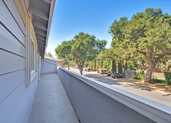 A long white building with a balcony overlooking a street.