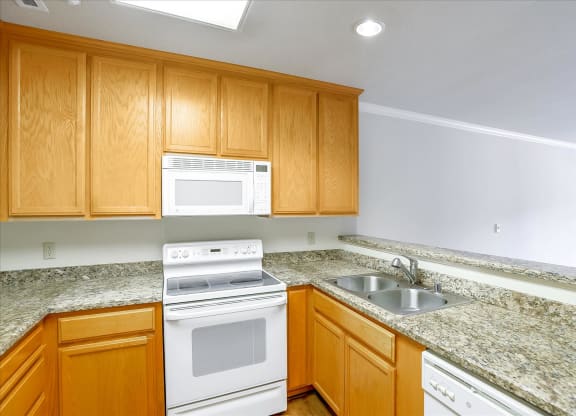 A kitchen with wooden cabinets and granite countertops.