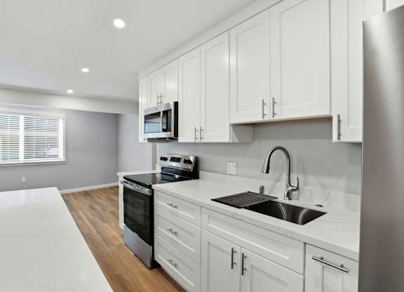 A modern kitchen with white cabinets and stainless steel appliances.
