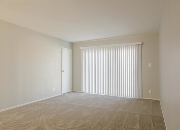 the living room of an apartment with a large window with white blinds