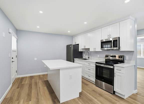 A kitchen with white cabinets and stainless steel appliances.