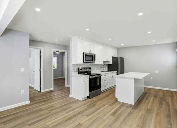 A modern kitchen with white appliances and wooden floors.