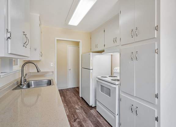 A kitchen with white cabinets and a stove top oven.