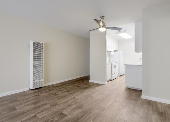 a living room and kitchen with wood flooring and a ceiling fan