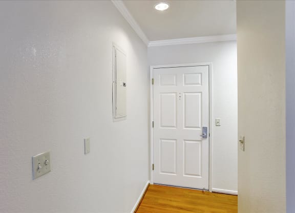 A white door is in a room with a light switch on the wall.