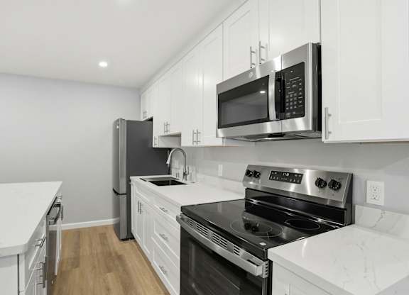 A kitchen with white cabinets and black appliances.