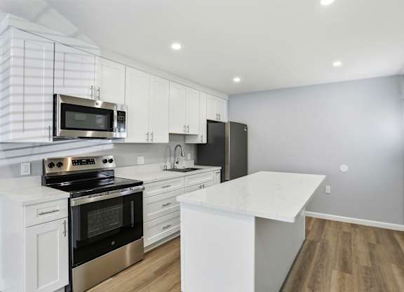 A modern kitchen with white cabinets and a black refrigerator.