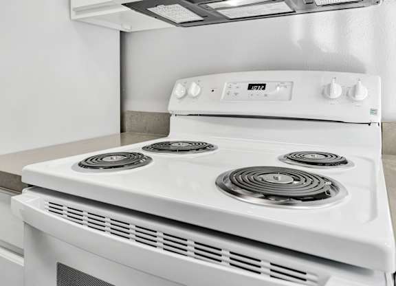 A white gas stove with four burners and a control panel.