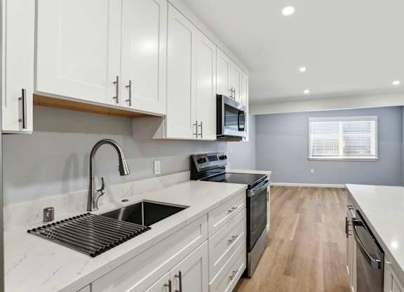 A modern kitchen with a sink, stove, and cabinets.