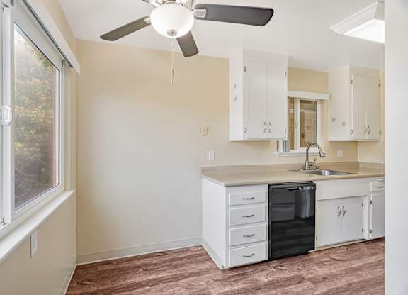 A kitchen with white cabinets and a black dishwasher.