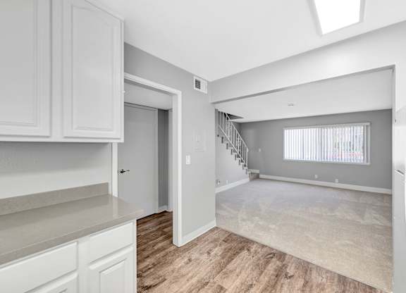 A spacious kitchen with white cabinets and a wooden floor.