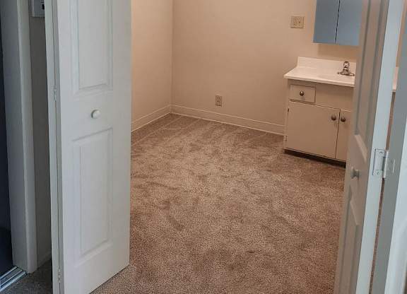 A white door is open to a room with a carpeted floor.