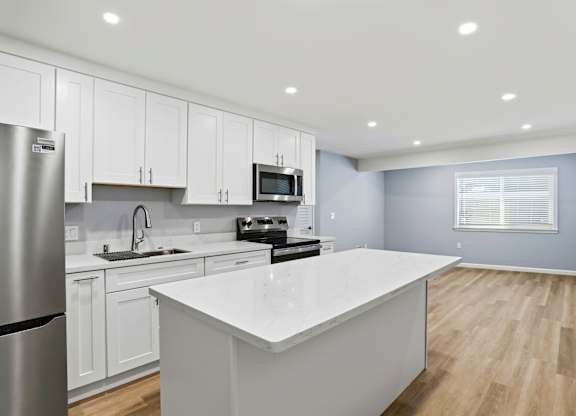 A modern kitchen with white cabinets and a large island.