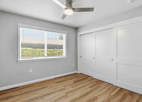 A room with a ceiling fan and a window with blinds.