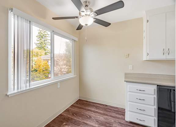 A room with a ceiling fan and a window with blinds.