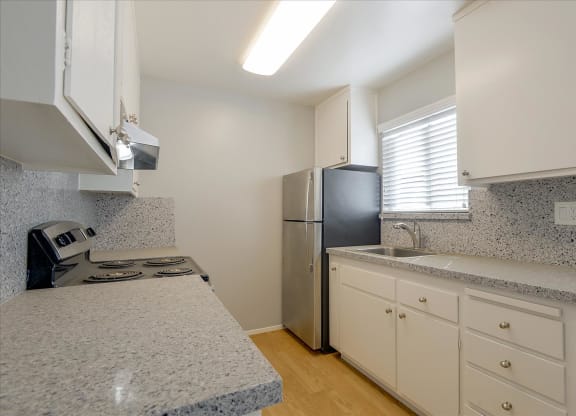 a kitchen with granite counter tops and a stainless steel refrigerator