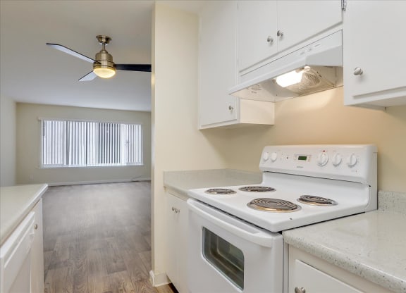 a kitchen with white appliances and a ceiling fan