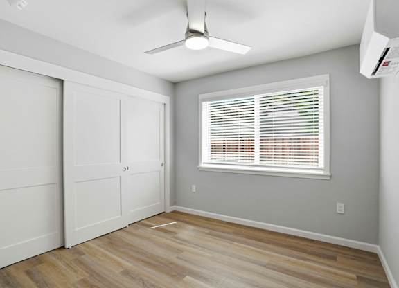 A room with a ceiling fan and a window with blinds.
