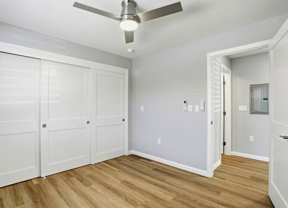 A room with a ceiling fan and white walls.